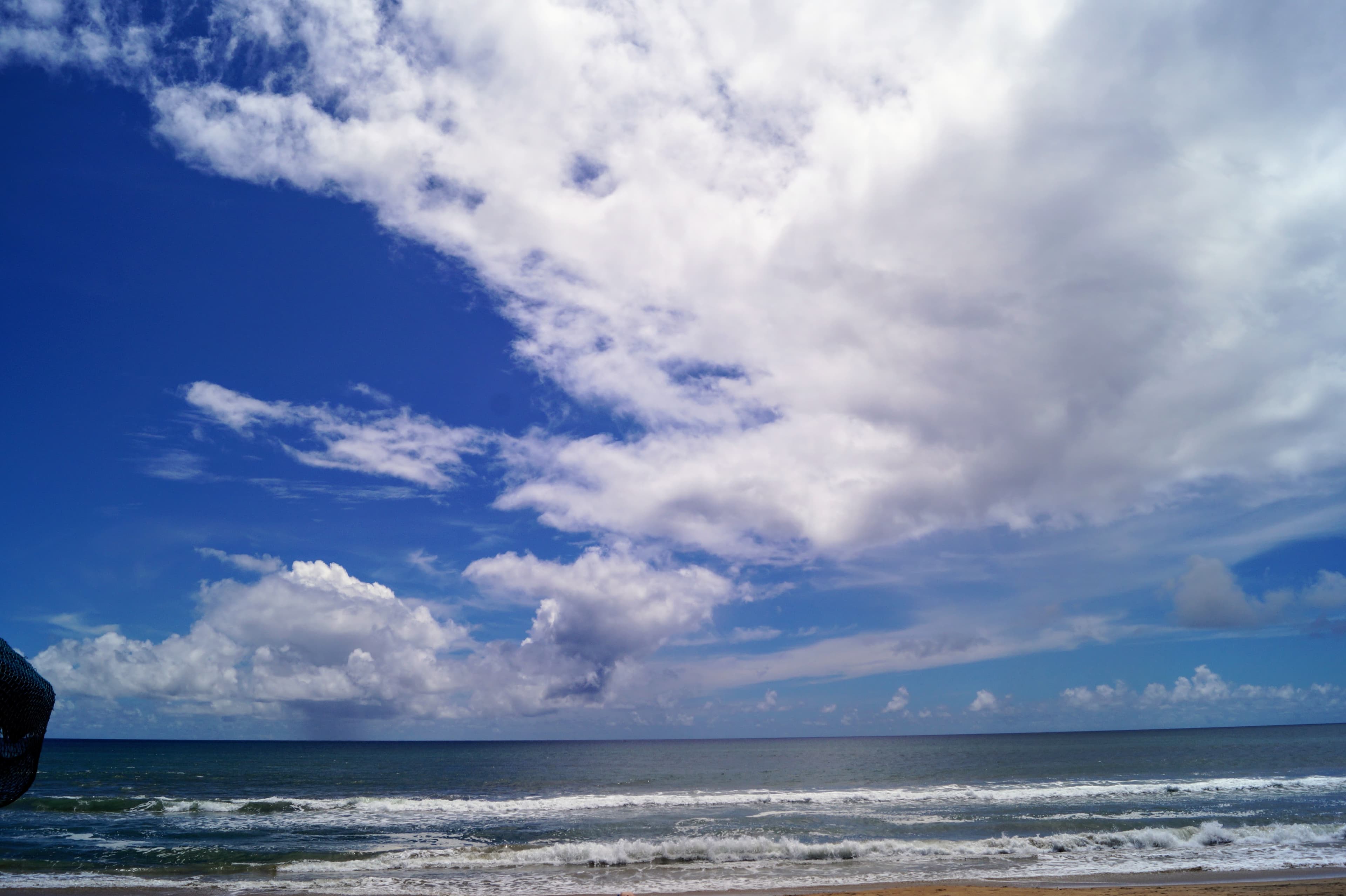 Ocean waves under a cloud-filled blue sky