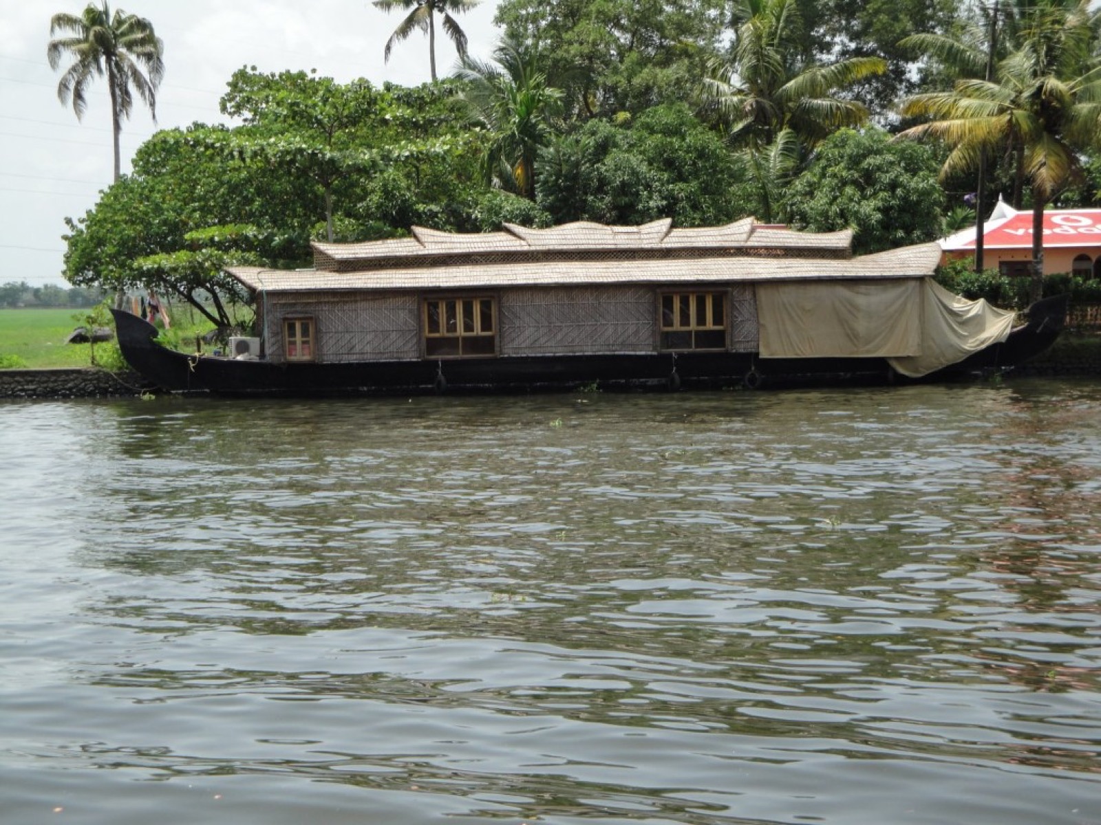 A thatched houseboat moored beside the Alleppey backwaters